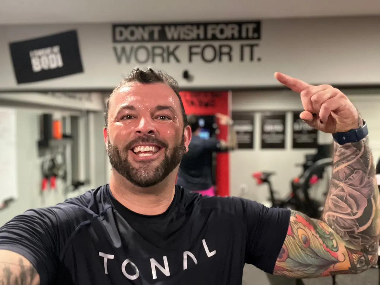 image (c1ba6ef0-f0d2-4948-8f30-f3bb0bb4ea9d) A man with tattoos is smiling in the gym.