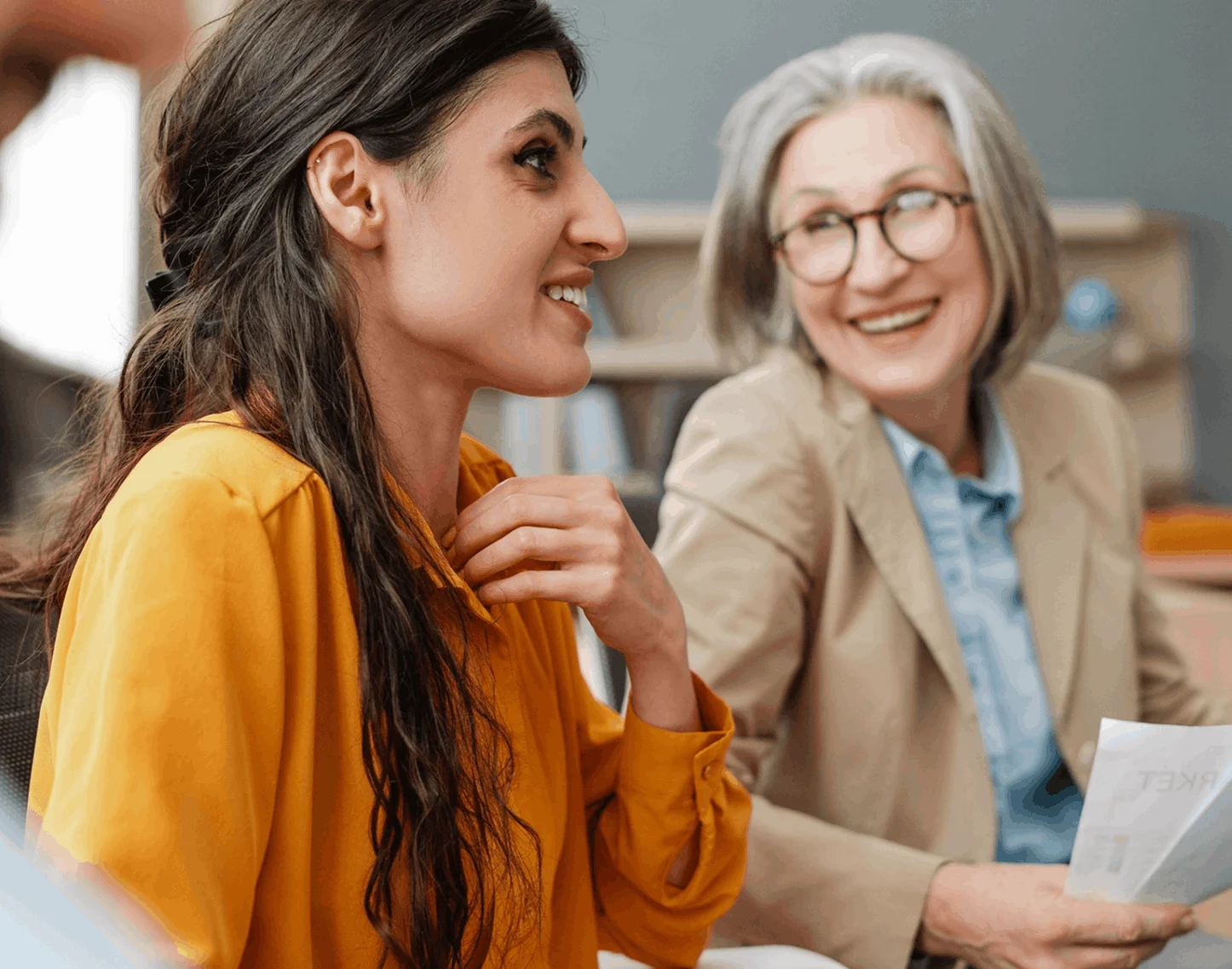 Two women sitting in a room talking to each other.