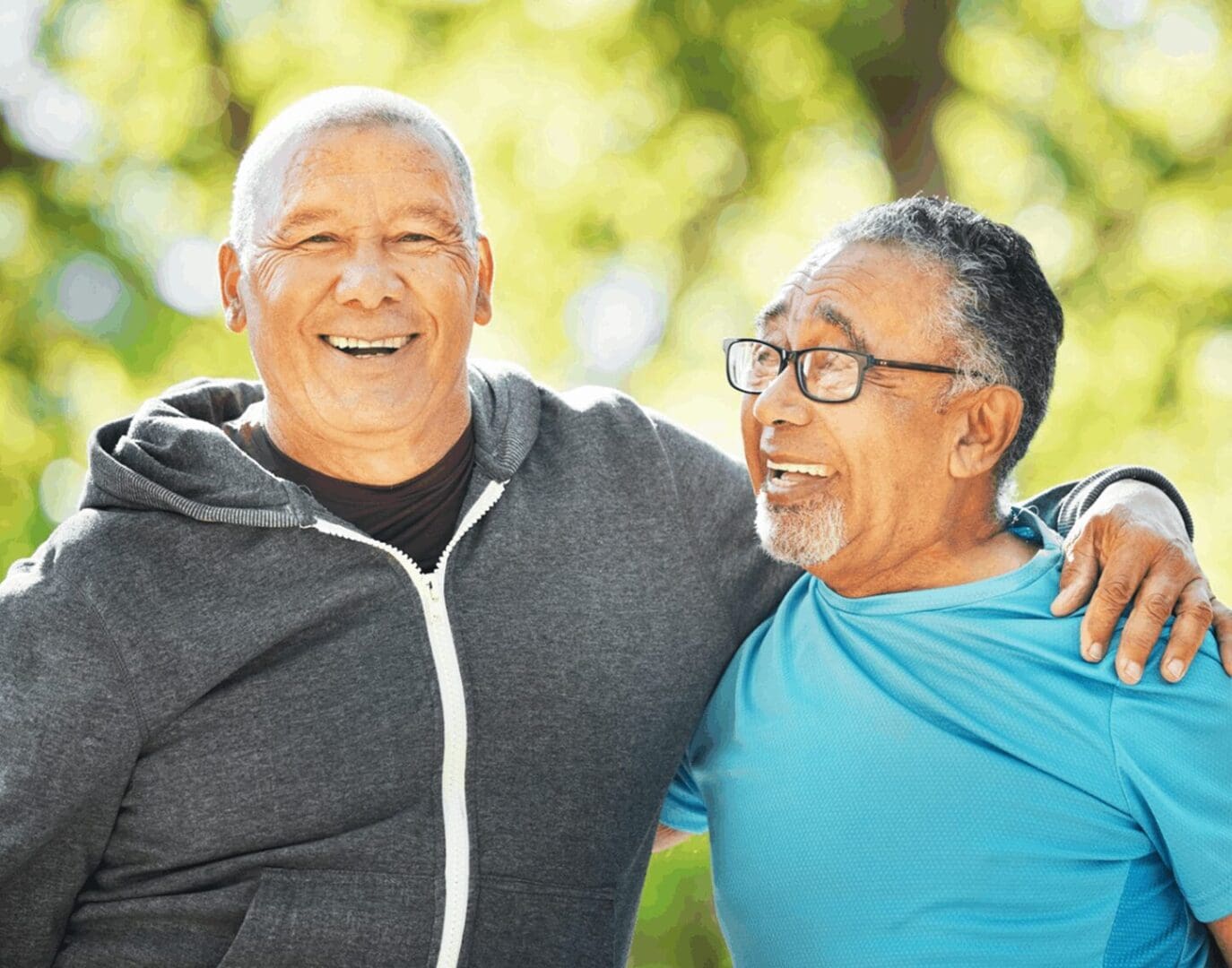 Two older men are smiling and hugging each other.